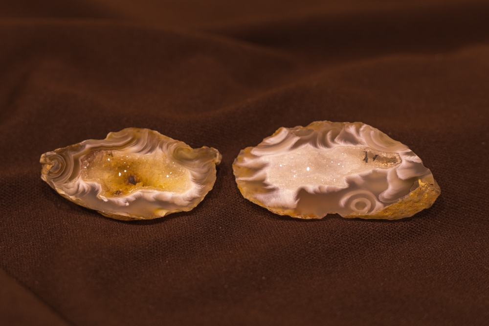 The two halves of white and golden colored interior of a thumb-sized geode.