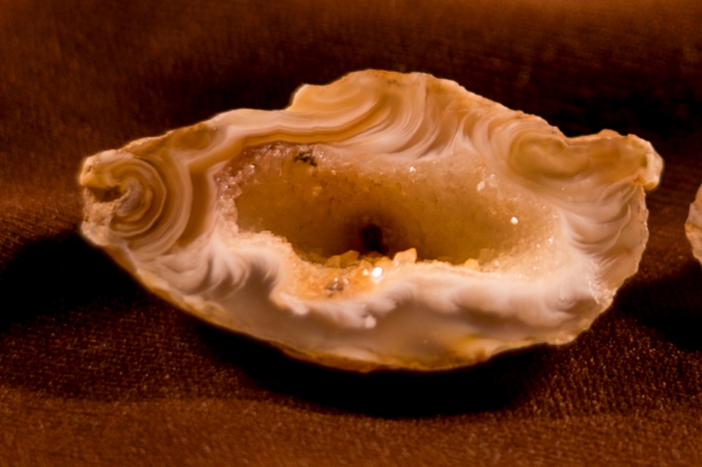 Gold and white swirls and crystals inside a thumb-sized geode.