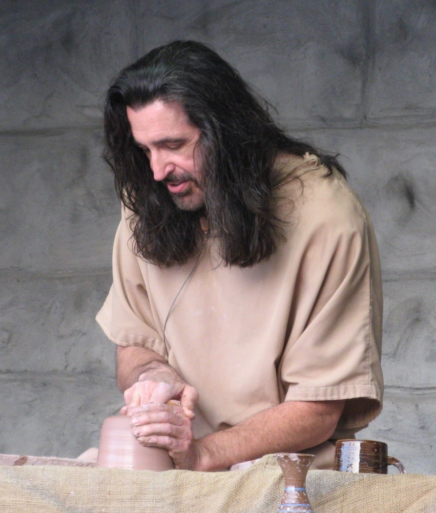 A potter centering and working with clay on his wheel.