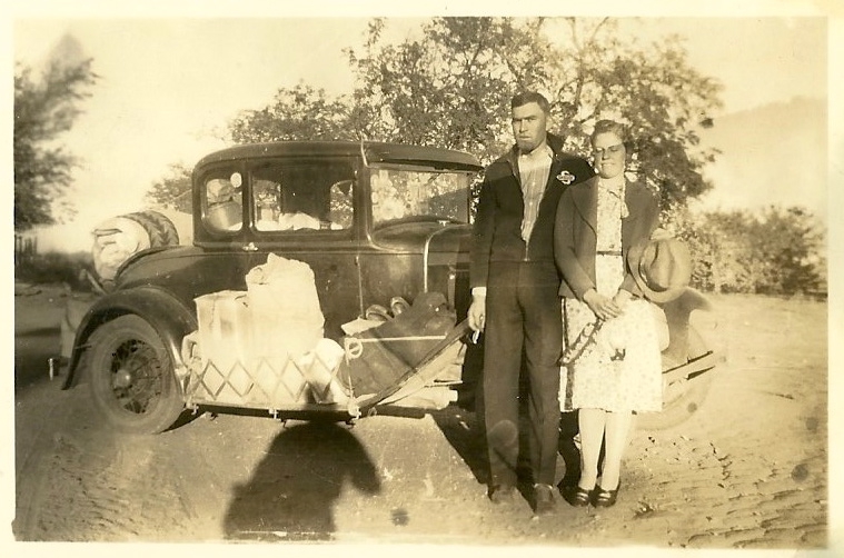 Young couple standing beside their Model A Ford that is loaded inside and outside.