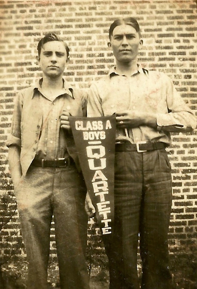 Buel M. Smith as a teenager holding winning pennant and standing beside another teenage boy.