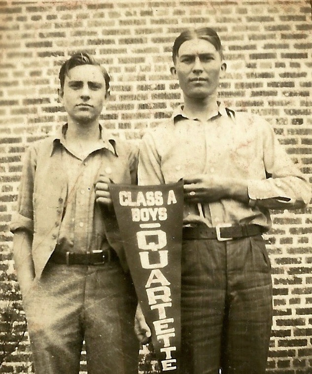 Buel M. Smith as a teenager holding winning pennant and standing beside another teenage boy.