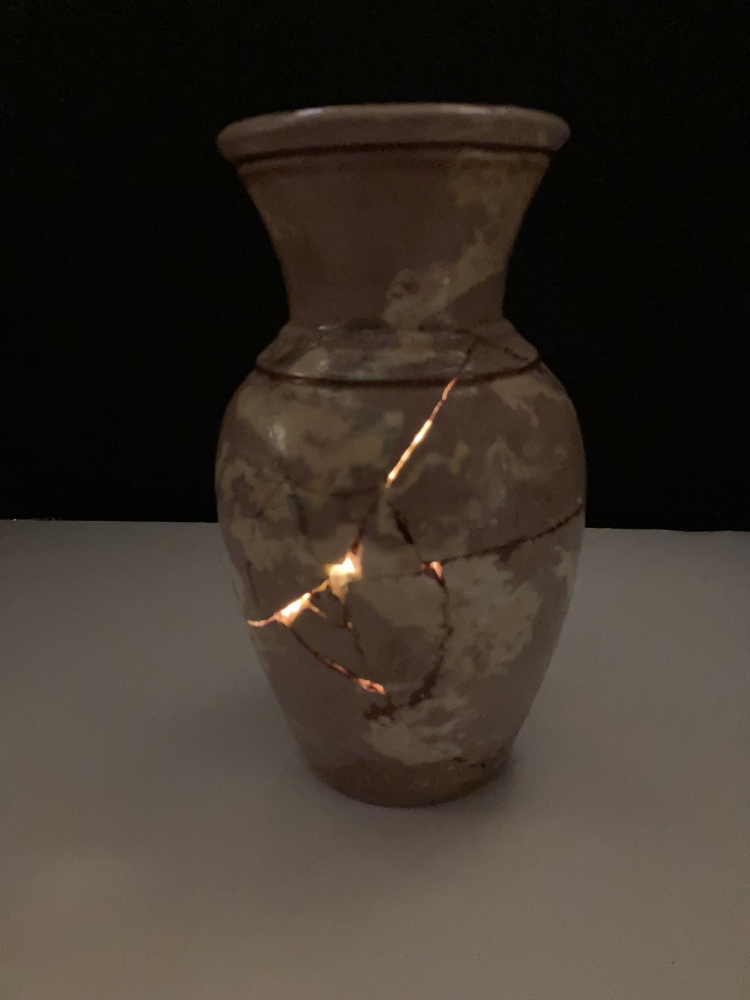 The vase, now glued together, has a light inside and light is showing through some of the cracks in it.