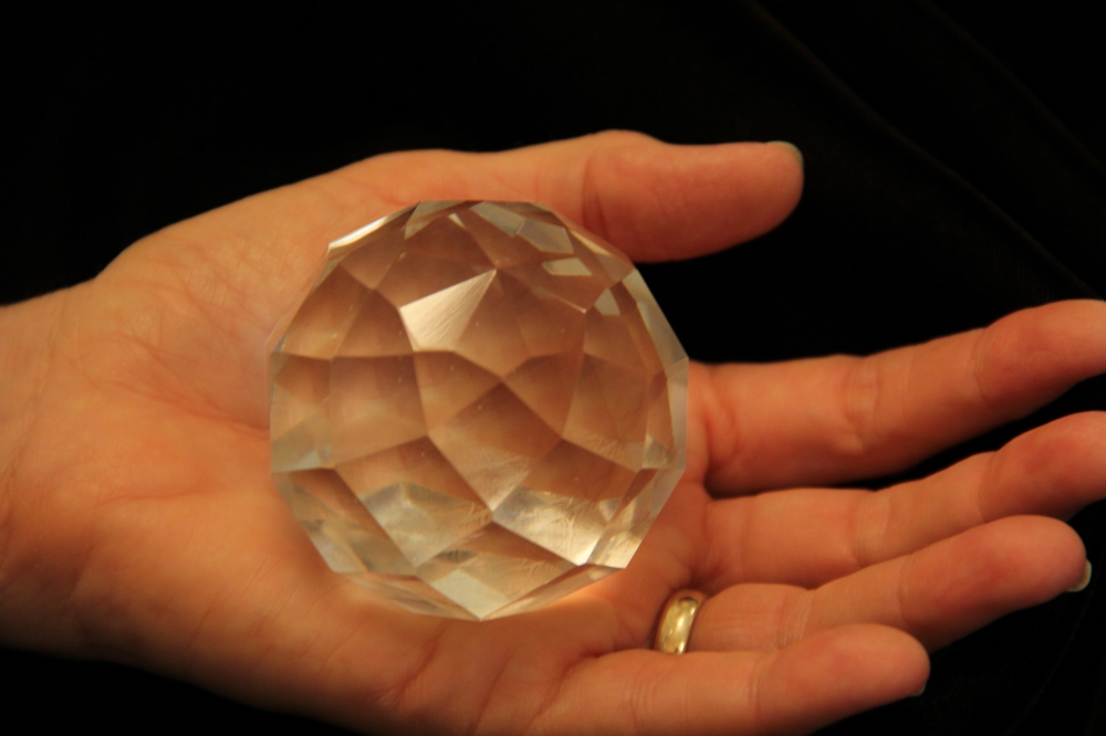 Hand holding large crystal paperweight.