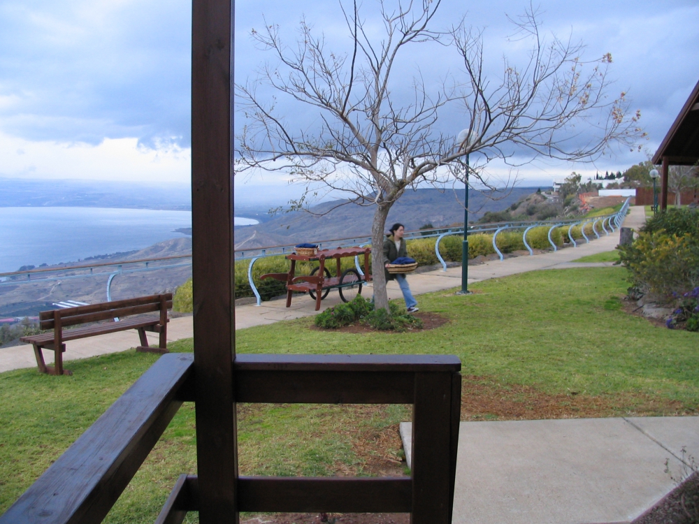 Woman delivering breakfast to overnight guests as they look out on view of Sea of Galilee.