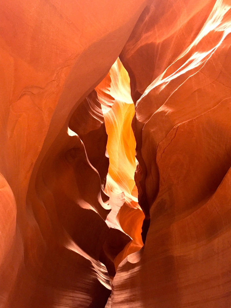 Orange and golden light shining down on rock formations from sun above the Upper Antelope Slot Canyon.