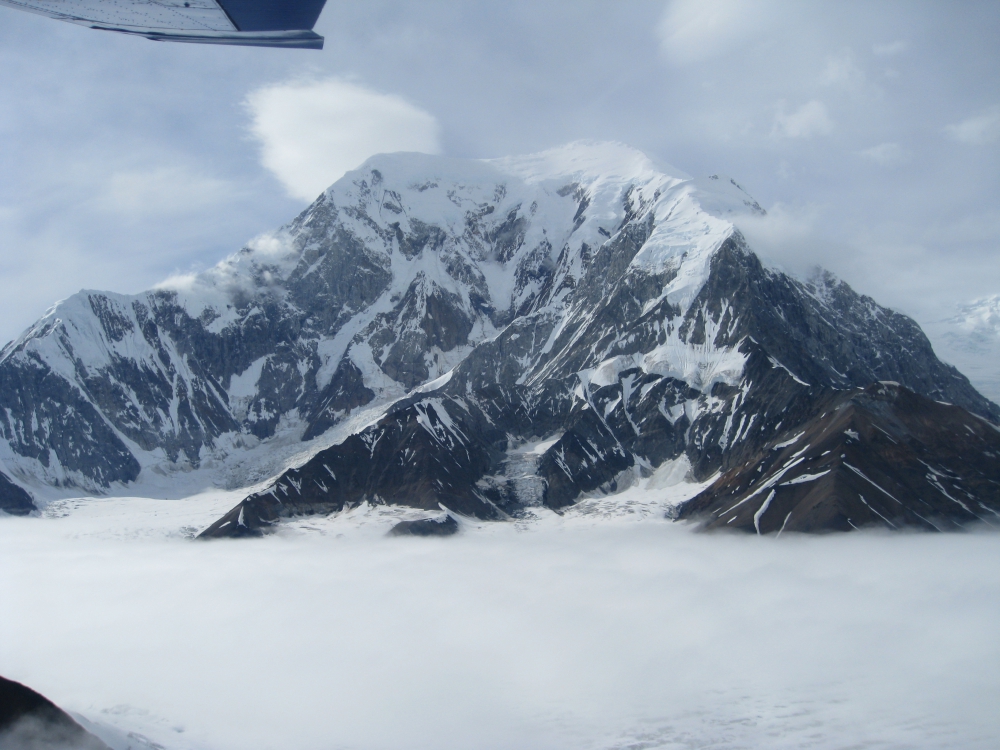 A closeup of a mountain peak sticking above the clouds.