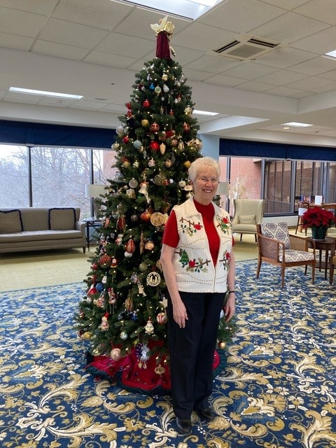 Phyllis Kester standing in front of a tall Christmas tree.