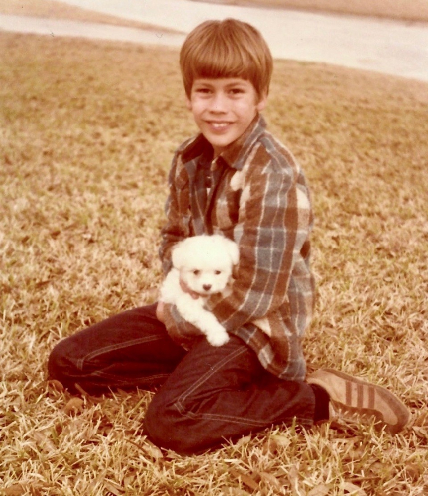 Ten-year-old boy holding young white cockapoo puppy.